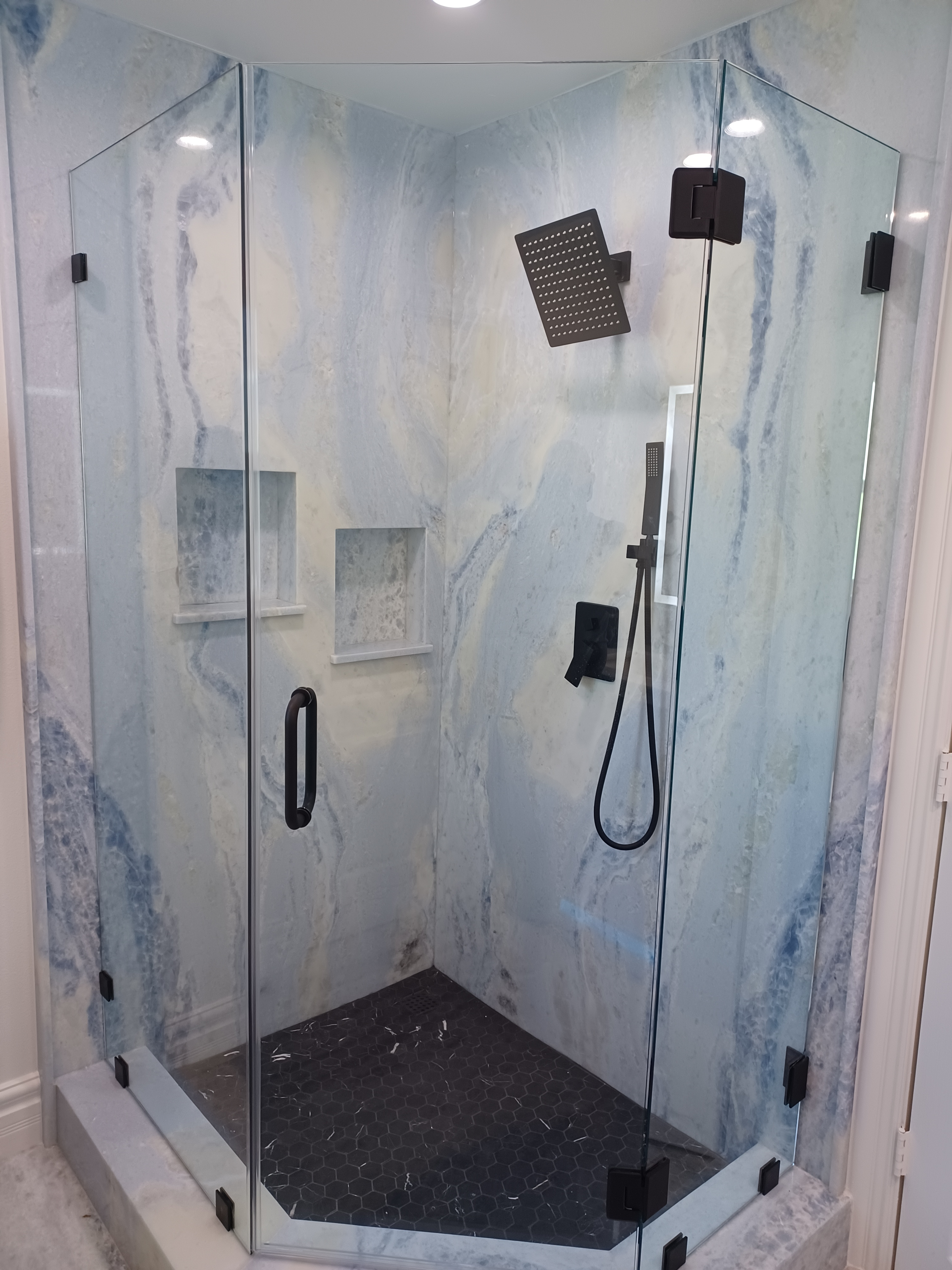 A shower with glass doors and black fixtures.